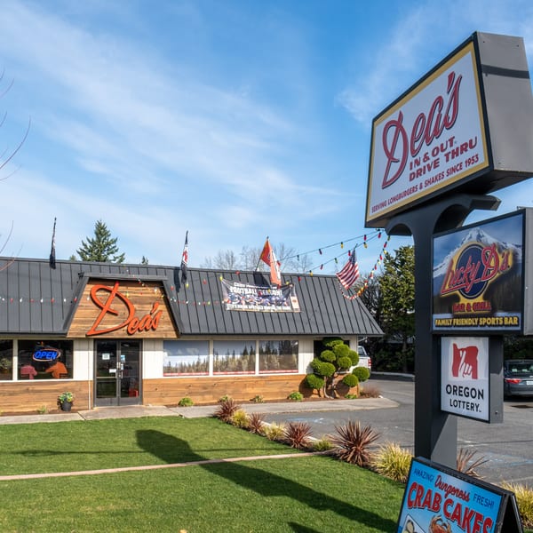 Exterior of Dea's In & Out restaurant with a large sign, drive-thru, and outdoor seating.