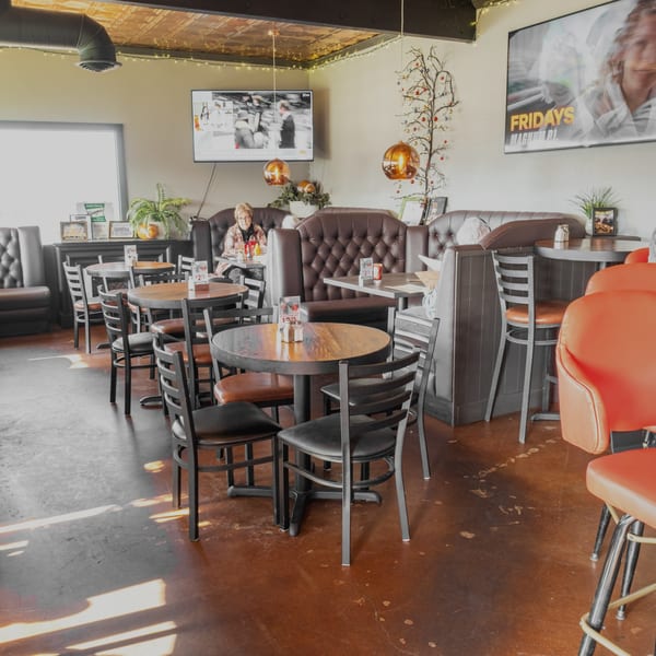 Dea's In & Out dining area with booths, tables, chairs, and a customer seated.