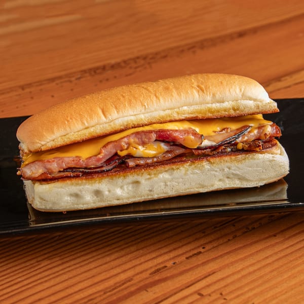 A Dea's In & Out burger with melted cheese and bacon on a black plate.