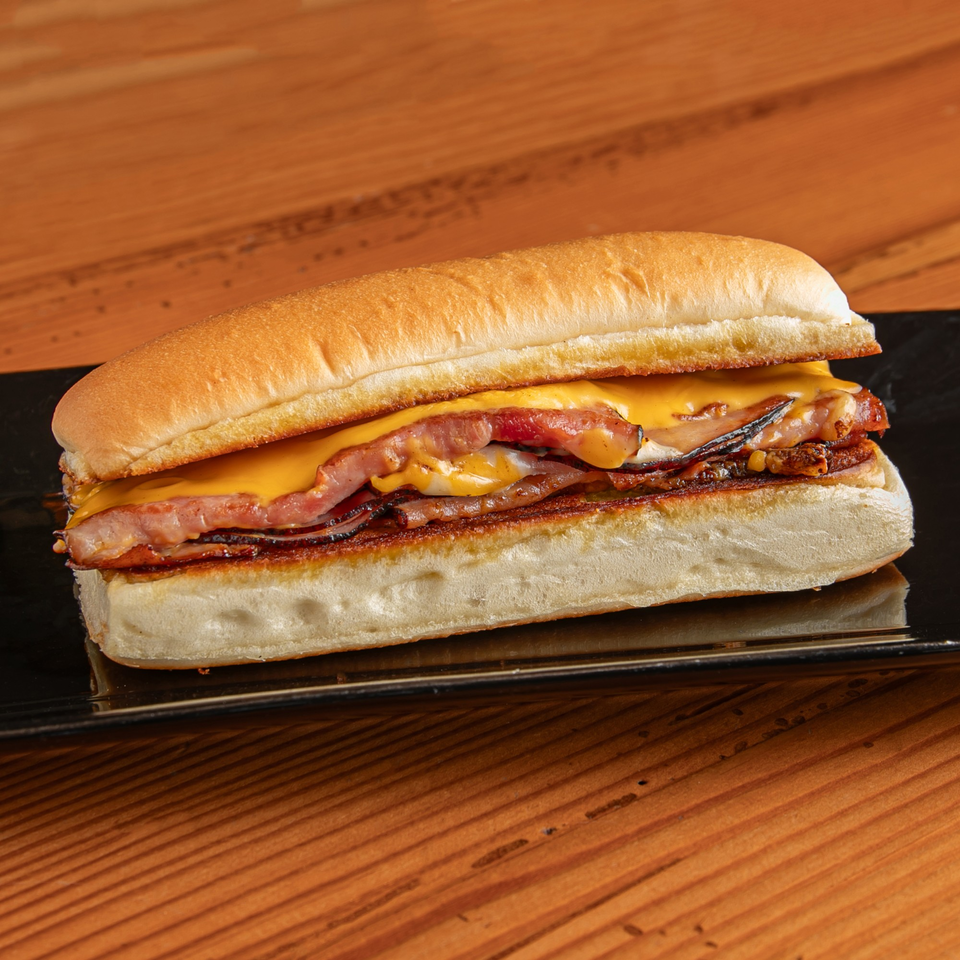 A Dea's In & Out burger with melted cheese and bacon on a black plate.