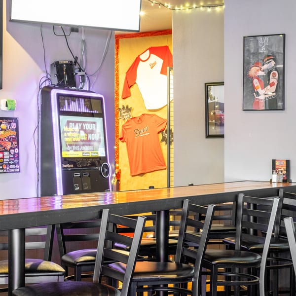 Interior of Dea's In & Out with a jukebox, branded merchandise, and bar seating.