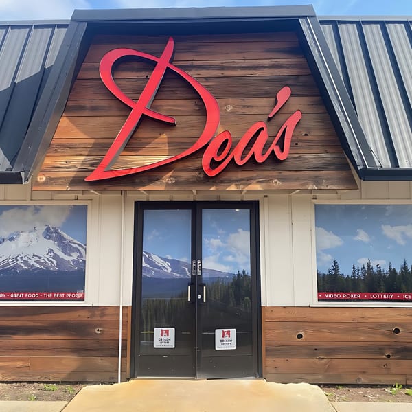 Dea's In & Out restaurant exterior with a large red sign, wooden facade, and glass doors.