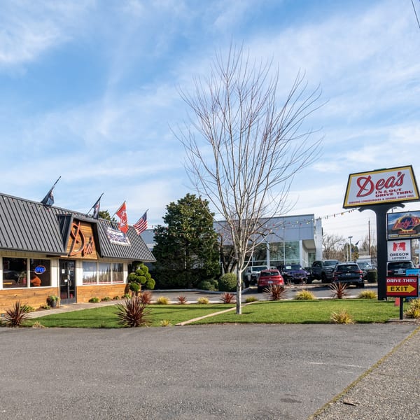 Exterior view of Dea's In & Out drive-thru restaurant with its sign and parking lot.