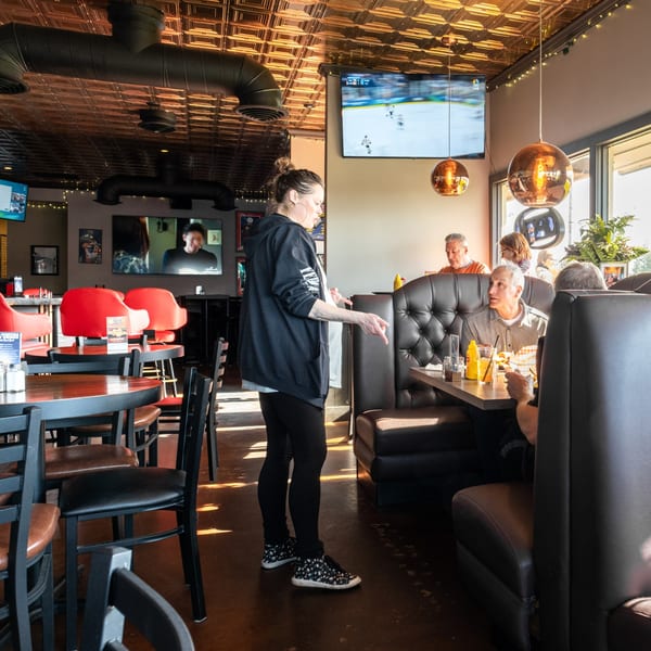 A server takes an order from customers seated in a booth at Dea's In & Out restaurant.